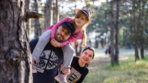 A joyful family enjoying a playful day in a sunlit forest park, capturing the essence of togetherness.